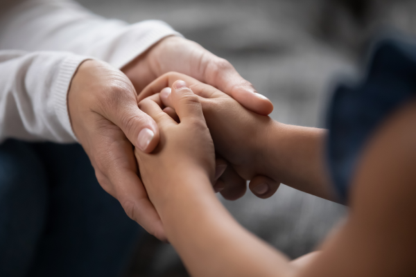 Adult hands holding a child's hands in support